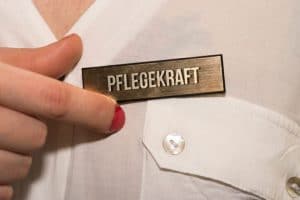 Frau pinnt sich 'Pflegekraft' Pin an die Bluse