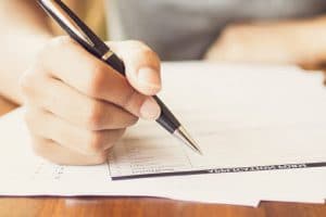 eine Hand füllt Dokument mit Stift aus