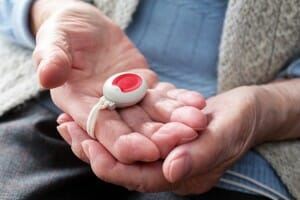 Hausnotrufknopf in der Hand einer Frau