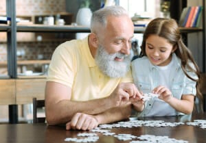 Kind spielt Puzzle mit älterem Mann
