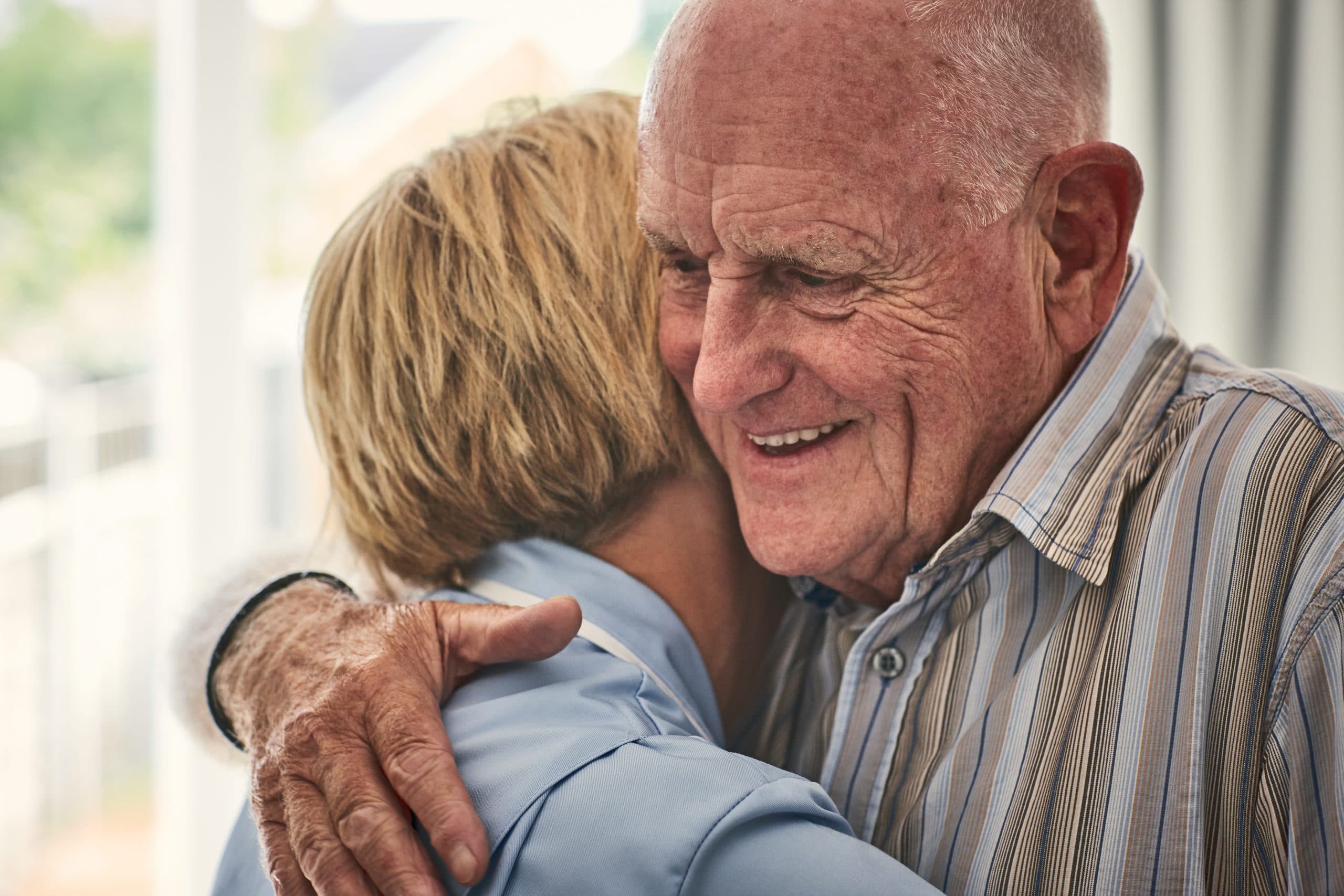 Älterer Mann umarmt lächelnd eine Frau