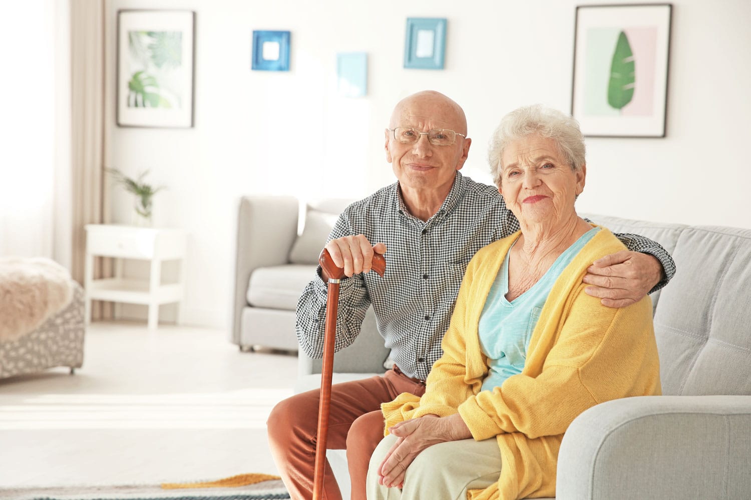 Älteres Ehepaar sitzt lächelnd auf Couch