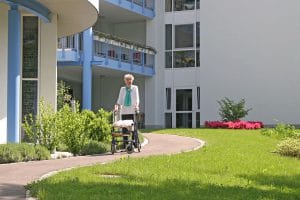 Alte Dame mit Rollator vor einem Pflegeheim