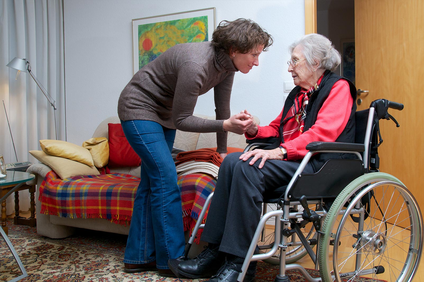 Frau redet mit alter Frau in Rollstuhl