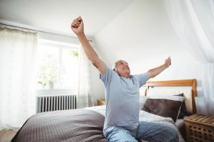 Mann streckt sich auf Bett vor Aufstehen