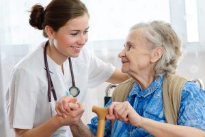 Pflegerin mit Stetoskop hält ältere Frau