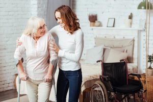 Junge Dame hilft Frau beim Gehen mit Krücke