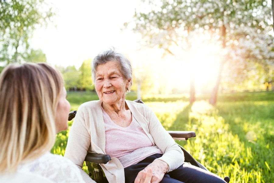 Glückliche Seniorin im Rollstuhl mit einer Pflegekraft